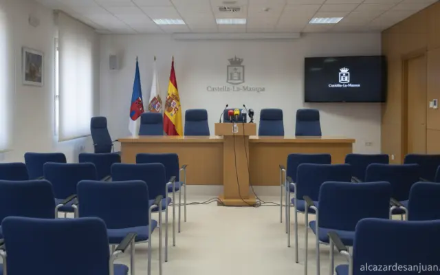 Journalistic photo of a Spanish regional government press conference room, a podium with microphones and institutional fla...