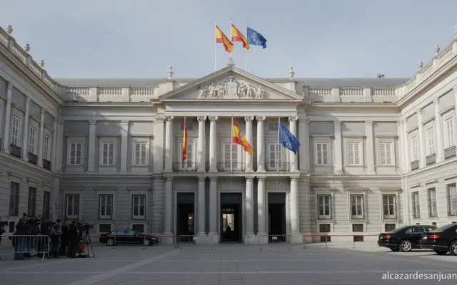 Journalistic photo of the exterior facade of the Moncloa Palace or a Spanish government press room with national and EU fl...