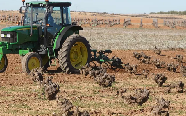 Tractor laboreando un viñedo en La Mancha a finales de invierno