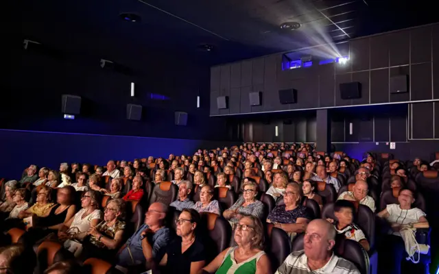 Personas mayores y familiares asisten a la proyección de cine en Multicines Cinemancha durante la Semana de los Mayores